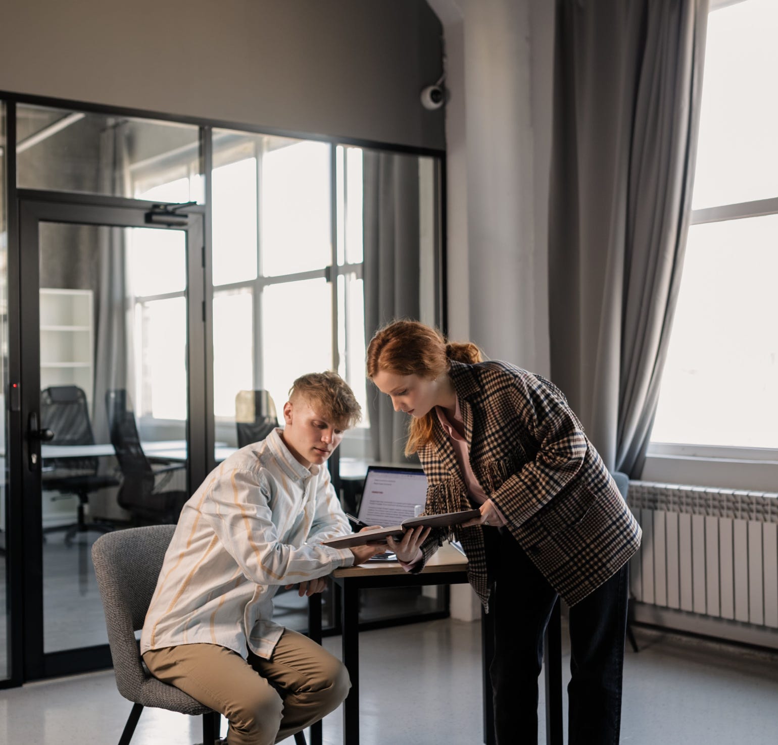 A Woman Standing Beside the Man Sitting on the Chair while Having Conversation